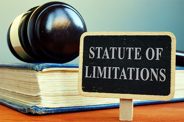 Book with gavel laying on top of it and sign that reads "Statute of Limitations"