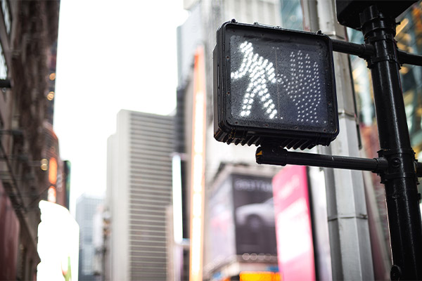 Sign on crosswalk signaling pedestrian to cross the intersection